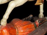 a statue of a man on a horse with a man laying on the ground