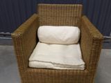 a wicker chair with pillows on it in a room
