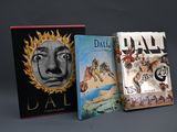 trois livres sont empilés sur une surface grise