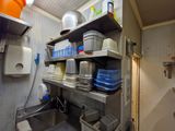 une petite cuisine avec un évier et des étagères remplies de vaisselle