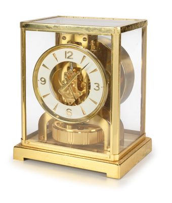 a gold clock with a face inside of a glass case