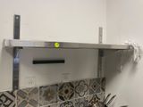 une étagère en acier inoxydable au-dessus d'une cuisinière, sur laquelle sont posées des casseroles et des poêles