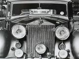 an old black and white photo of a classic car with a clock on the front of it