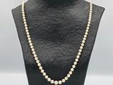 a white pearl necklace on a black mannequin
