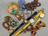 a lot of jewelry on a table with a watch and a pen