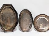 three silver plated objects are sitting next to each other on a white surface