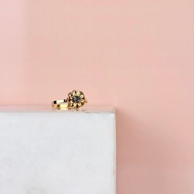 une image représentant une bague en or sertie d'un diamant bleu, posée sur un bloc de marbre blanc