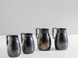 trois pichets en argent posés les uns à côté des autres sur une table blanche