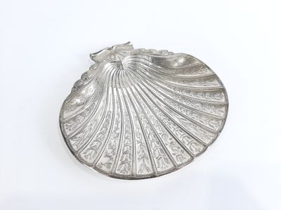 petit bijou argenté en forme de coquillage sur fond blanc