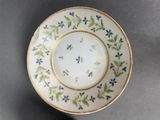 a close up of a plate on a table with blue flowers on it