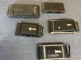 five old cell phones sitting on a blue surface