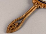 a gold spoon with a mirror on it on a table