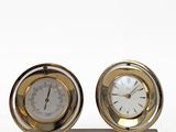 two clocks sitting on a stand on a white surface