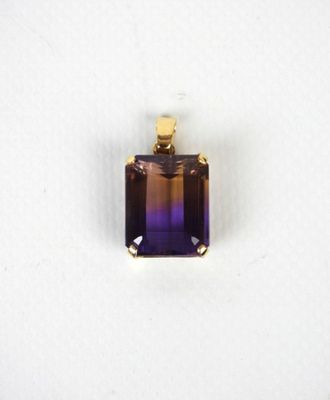 un gros plan d'un pendentif violet et jaune sur une surface blanche