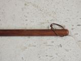 a wooden stick with a metal handle on a floor