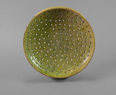two green and white bowls with holes in them on a gray surface