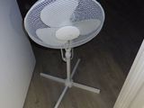 une table blanche sur laquelle est posé un ventilateur, dans un coin de la pièce