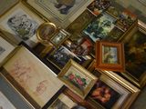 a lot of framed pictures on the floor next to a clock