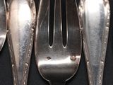 five silver spoons and two silver spoons on a table