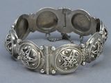 an antique silver bracelet with ornate design on a gray surface