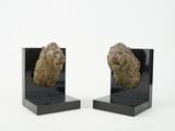 pair of art deco bookends of a lion head on a black marble base