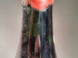 a close up of a wine bottle with a flower in it