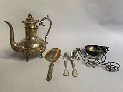 une théière en argent, des cuillères et des ustensiles posés sur une table