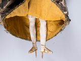 a doll that is wearing a yellow dress and holding a yellow umbrella