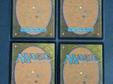 four magic the gathering booster cards are shown on a table