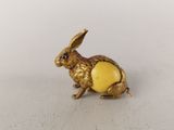 une image représentant une figurine de lapin en or posée sur une surface blanche