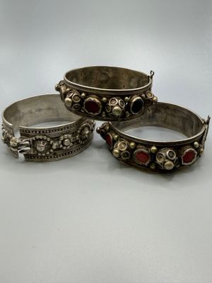 trois bracelets en argent ornés de pierres rouges et vertes