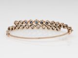 a close up of a gold bracelet with blue and white stones