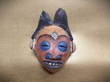 a clay mask with blue eyes on a gold surface
