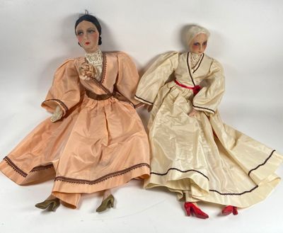 two dolls are sitting next to each other on a white surface