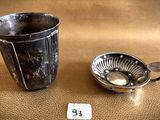 a silver cup and a silver spoon on a table