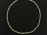 un collier de perles avec un fermoir en or sur fond noir
