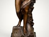 an antique bronze statue of a woman holding a flower