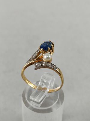 a close up of a gold ring with a sapphire and a pearl