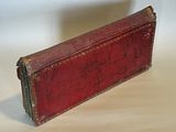 an old red book sitting on a white surface