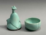 a small vase and a small bowl sitting next to each other