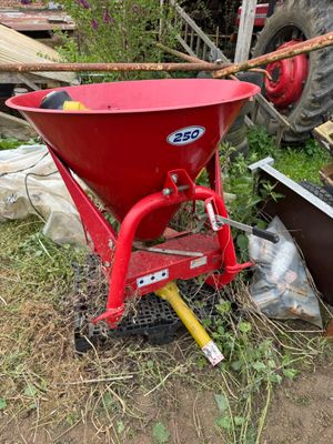 a red wheelbarrower sitting in the grass next to a pile of junk