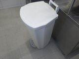 des toilettes blanches situées dans une salle de bains, à côté d'une poubelle