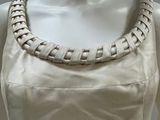an image of a mannequin wearing a white dress with a braided neckline