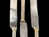 three pieces of silverware on a black surface with a black background