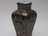 un petit vase posé sur une surface blanche