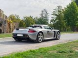 a silver sports car driving down the road in front of a castle