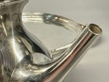 a silver tea pot with a handle on a table