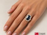 woman ' s hand with a diamond and sapphire ring on it ' s finger