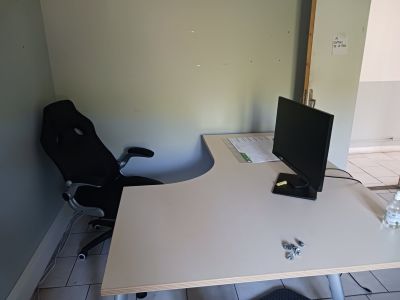 un bureau avec un ordinateur et une chaise dans un coin