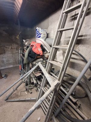 une échelle appuyée contre un mur, à côté d'un tas de métal